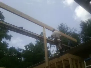 Carpenter setting a ridge beam over a new addition frame — Ice Dam Removal by Roofing Brothers in Davidsonville