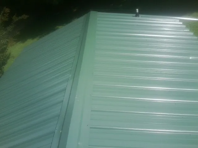 New green metal panels meeting at the ridge of a roof — Flat Roof Repair work by our crew in Davidsonville