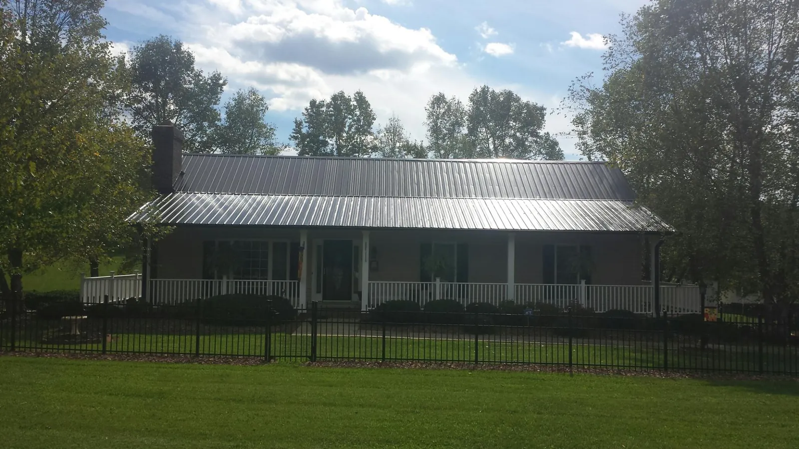 Gray metal roof on a brick ranch with a full width front porch — Gutter Guard Installation work by our crew in Davidsonville
