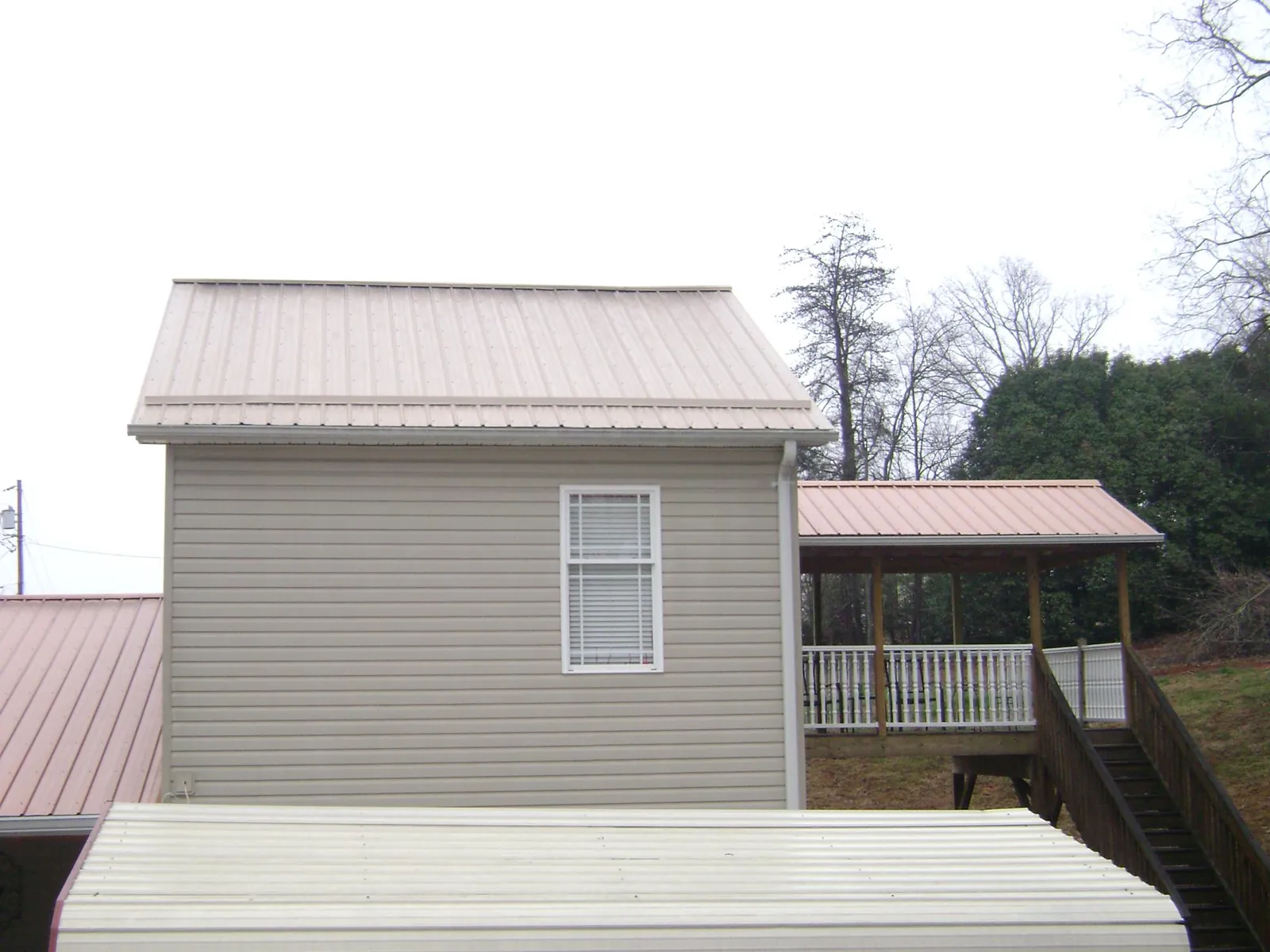 Tan metal roofs on a two story addition and attached porch, from a Roof Replacement job in Davidsonville