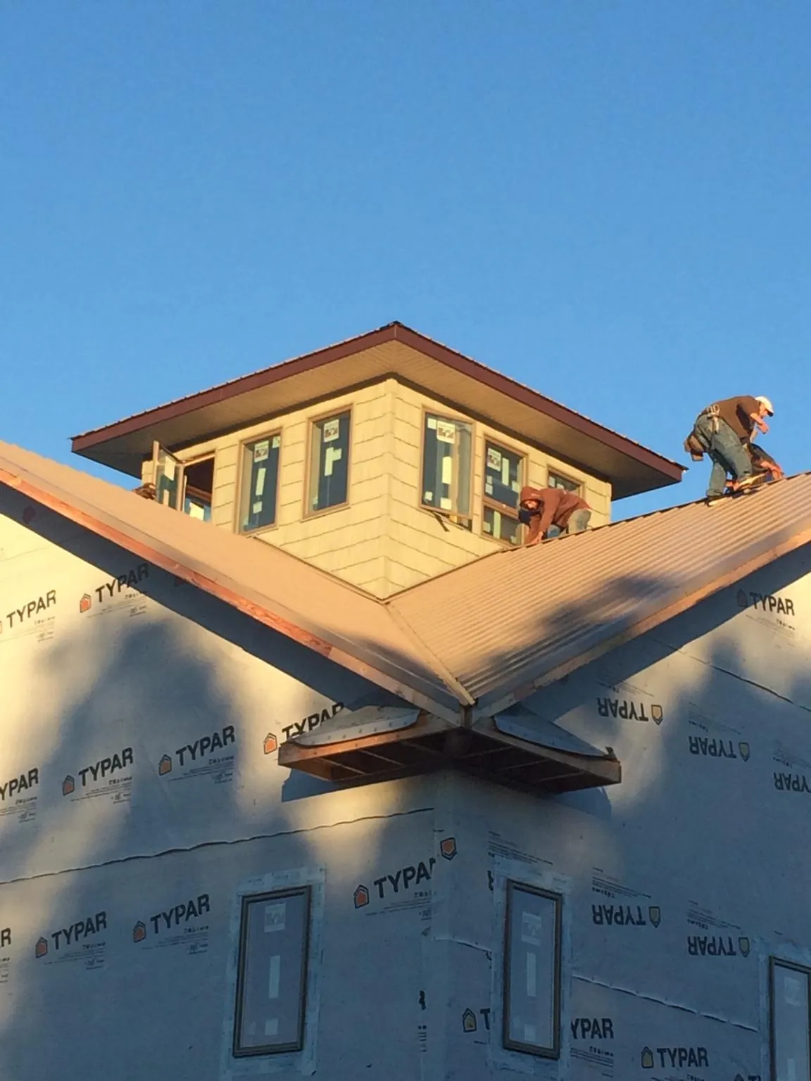Roofers working around a rooftop cupola on a new metal roof at sunset — Roof Waterproofing in Davidsonville by Roofing Brothers